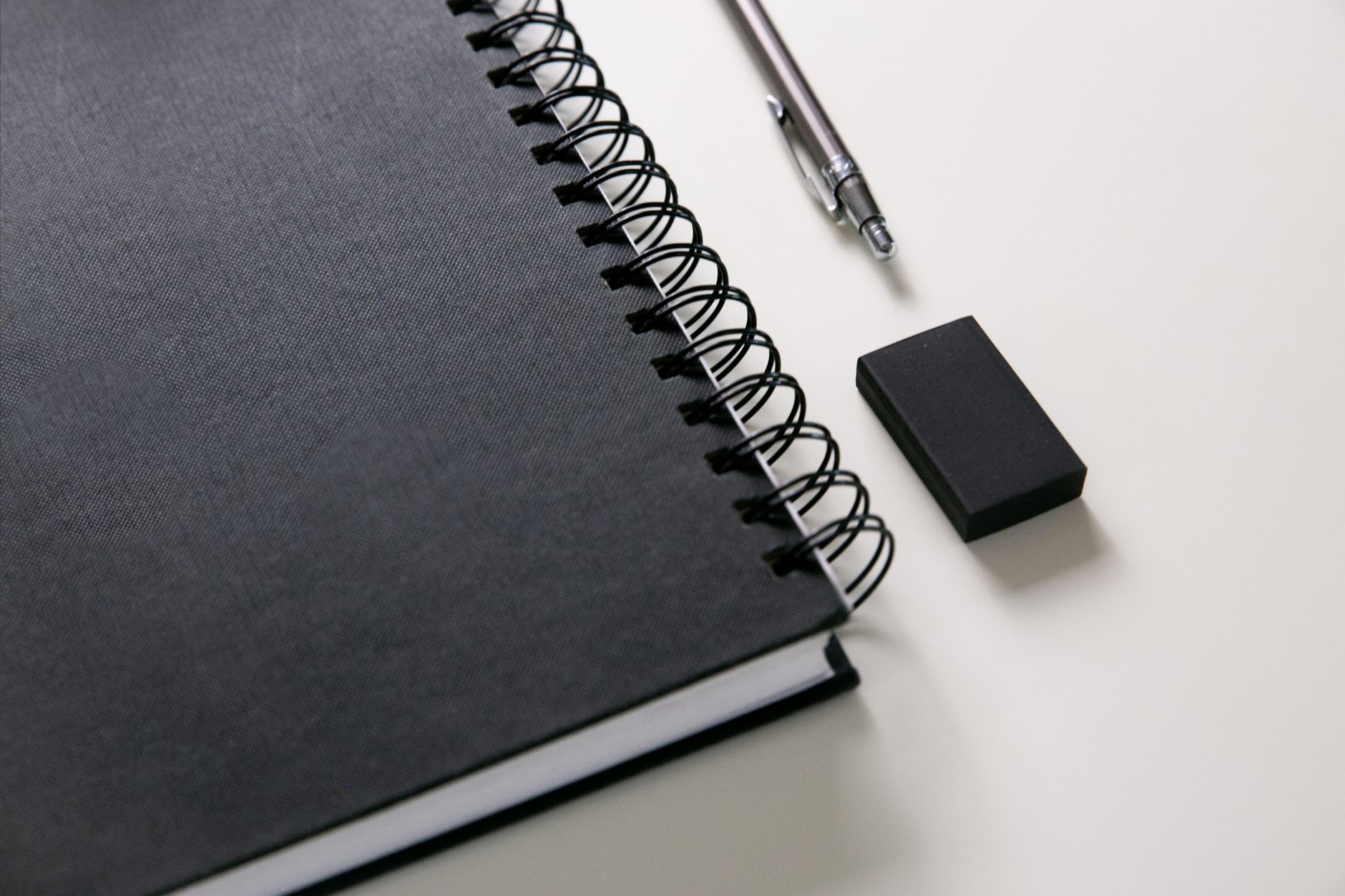 A dark notebook, pen, and eraser arranged as a quiet reflection still life.